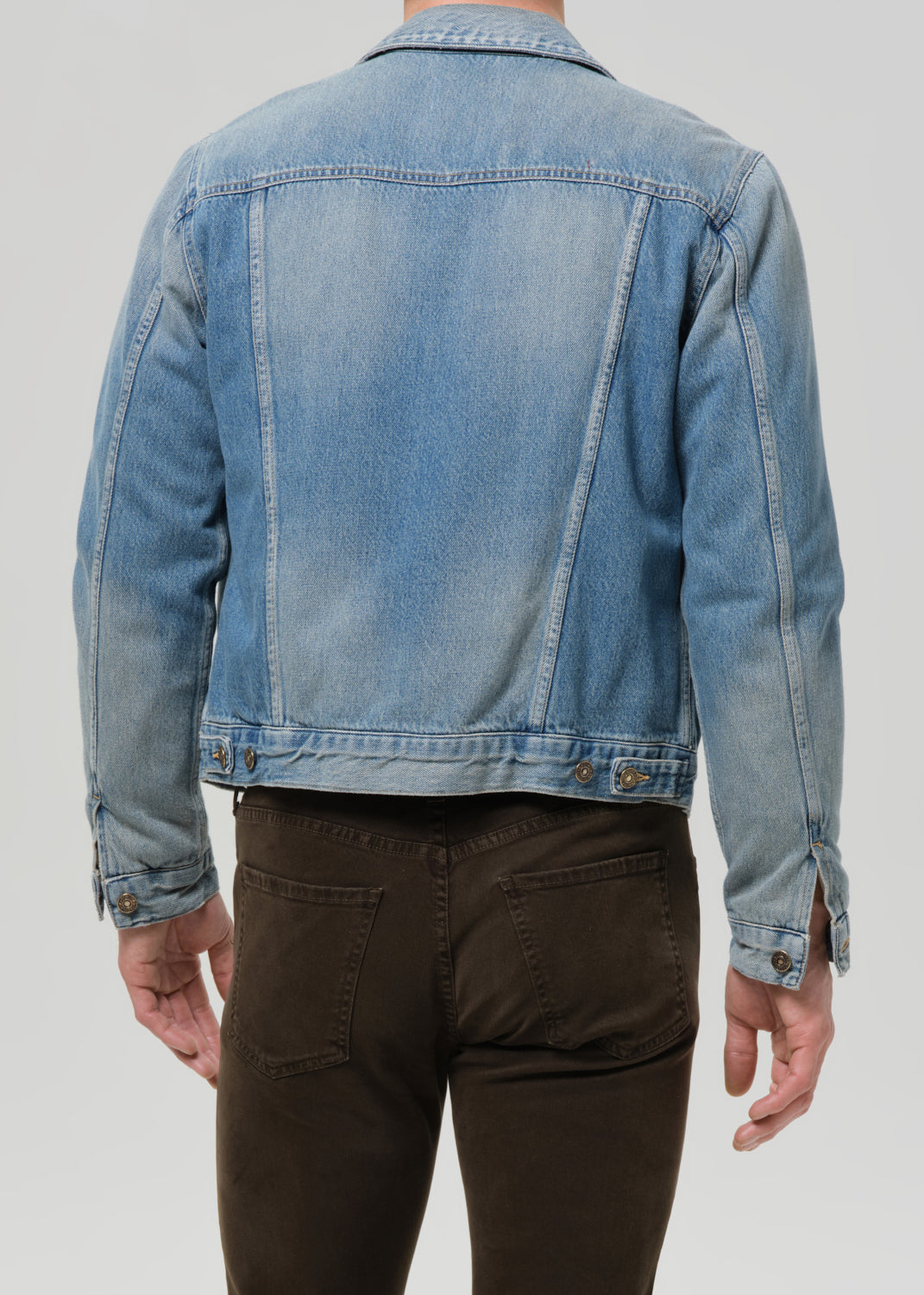 Person wearing a light blue denim jacket on a grey background