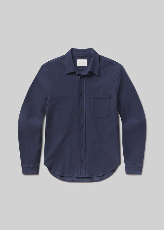 Flat lay shot of navy blue button-up shirt on a grey background