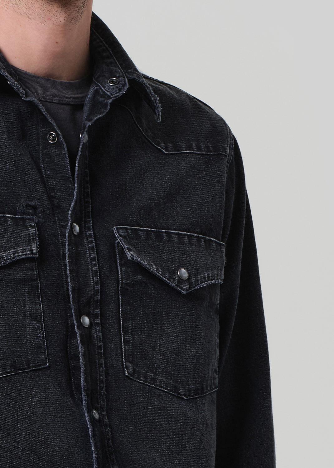 Close-up of a black denim jacket with pocket details.