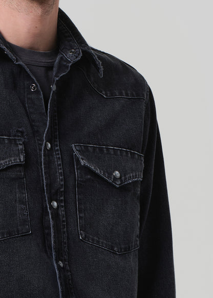 Close-up of a black denim jacket with pocket details.