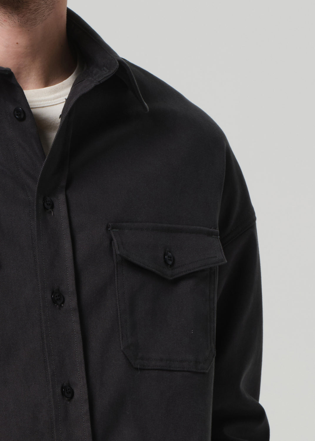 Black shirt with pocket detail on a plain background