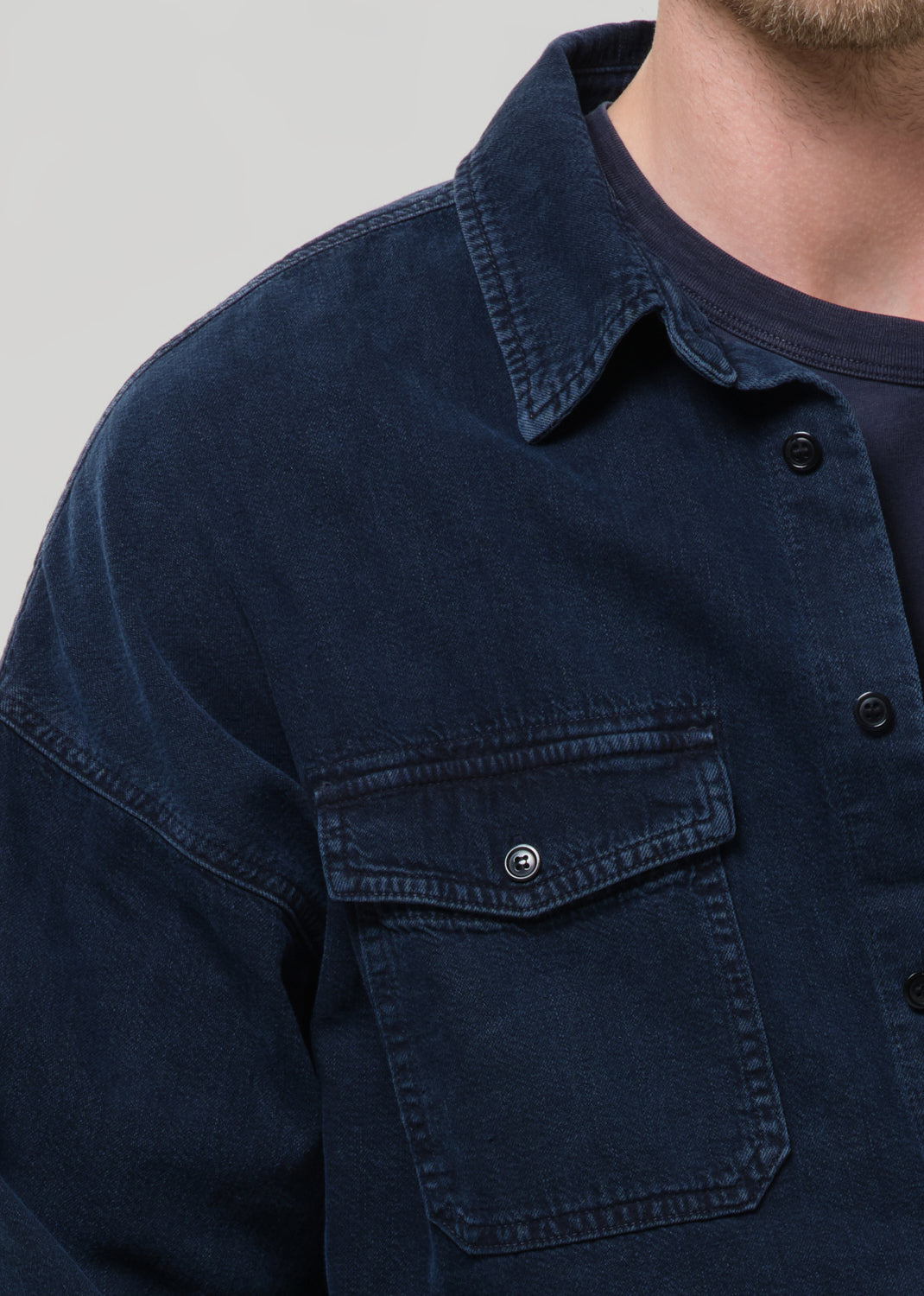 Close-up of a dark navy button-up shirt on a grey background.