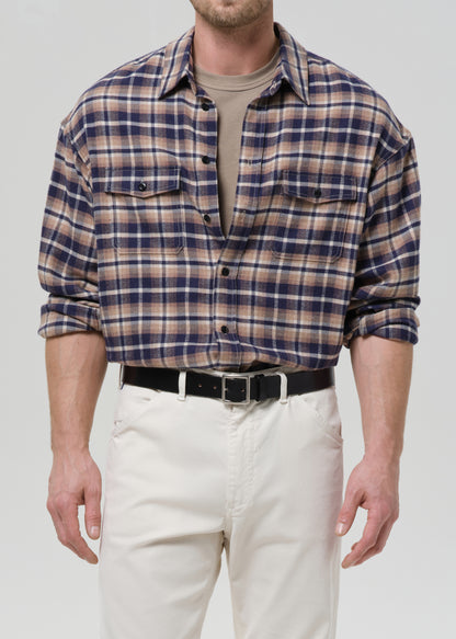 Man wearing a plaid shirt and white pants on a grey background