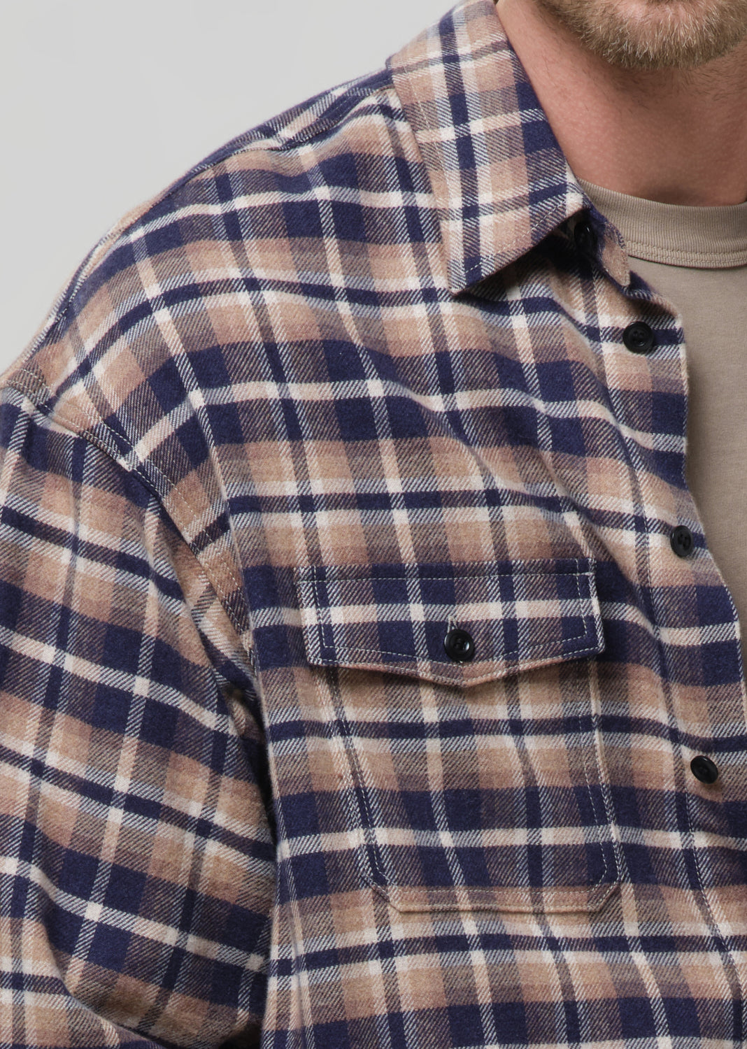 Close-up of a person wearing a plaid shirt with a grey background