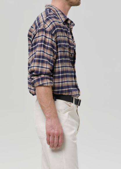 Person wearing a plaid shirt and white pants on a grey background