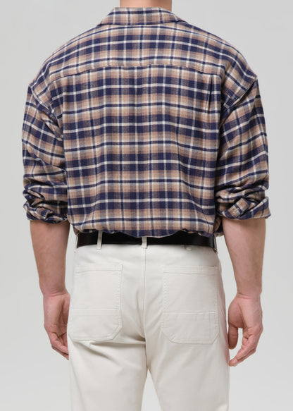 Person wearing a plaid shirt and white pants on a grey background