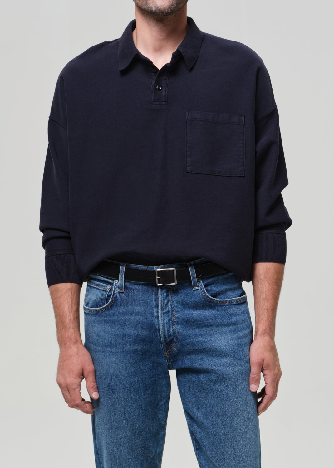 Person wearing a navy blue shirt and blue jeans on a plain background