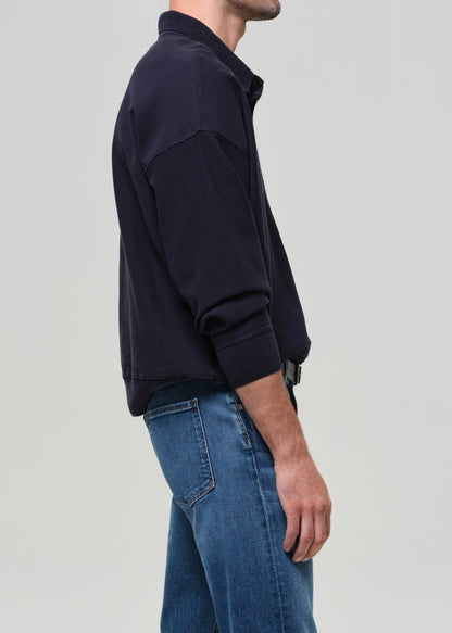 Person wearing a dark blue jacket and jeans on a light gray background