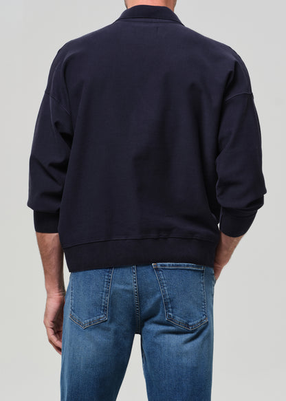 Person wearing a navy jacket and blue jeans on a light gray background