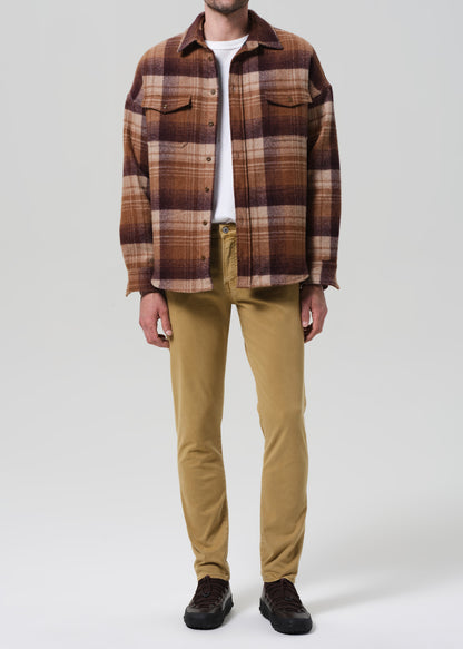 Person wearing a plaid shirt and tan pants on a neutral background