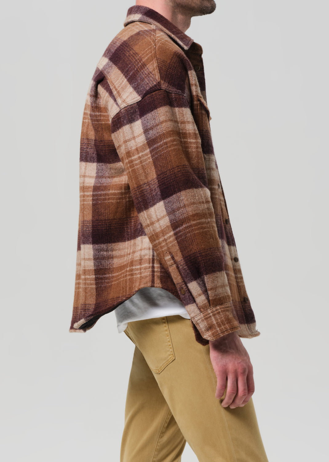 Person wearing a plaid shirt and khaki pants on a neutral background
