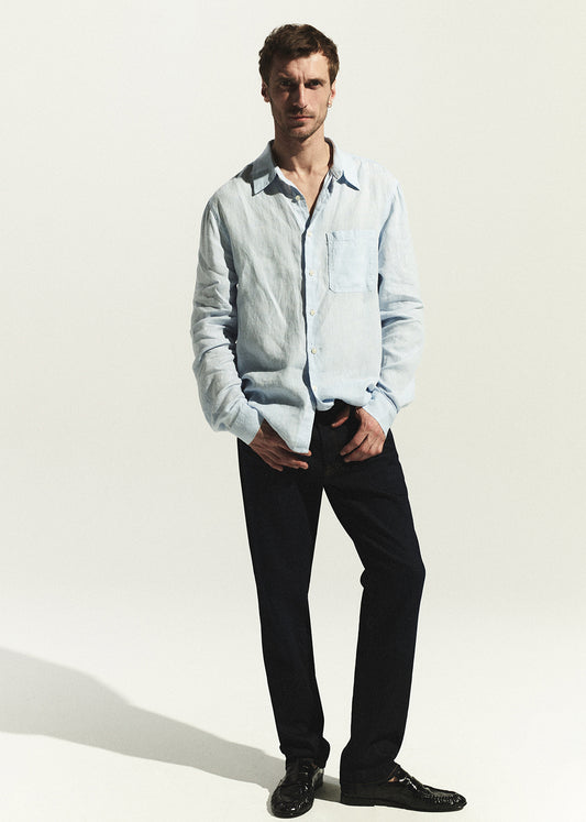 Man wearing a light blue shirt and dark wash jean on a white background