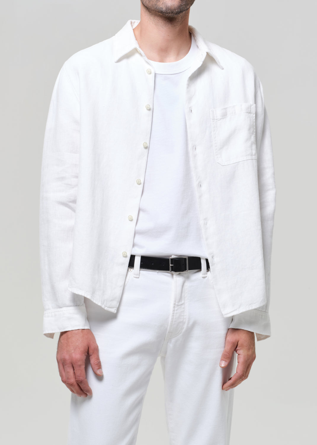 Person wearing a white shirt and pants with a gray background