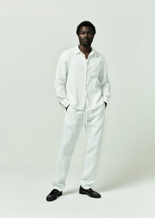 Man wearing a white outfit with black shoes on a plain background