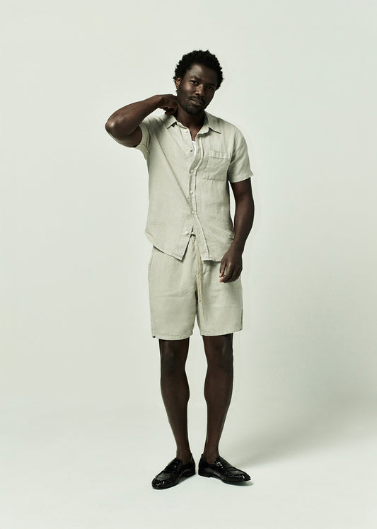 Man wearing a linen beige shirt and shorts set on a grey background