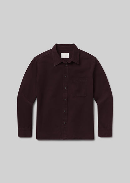 Flat lay of dark red button-up shirt on a grey background