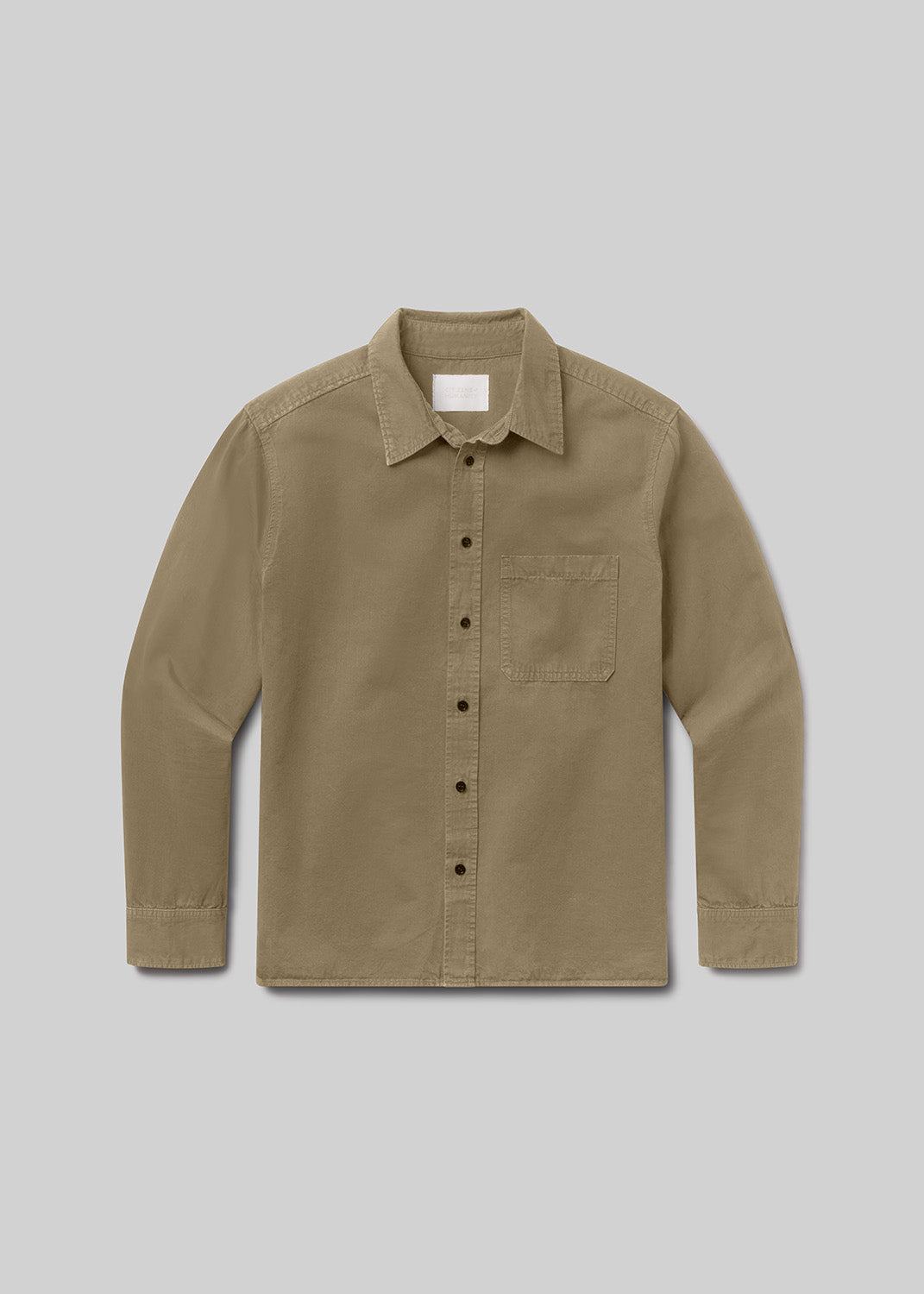A long-sleeve button-up shirt in a warm khaki or tan color, featuring a classic collar, a single chest pocket, and dark buttons, displayed against a grey background.