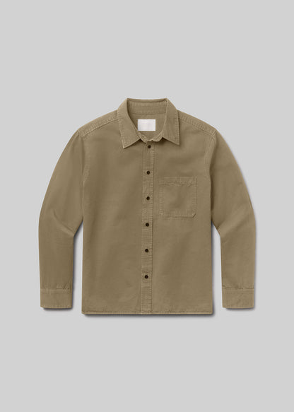 A long-sleeve button-up shirt in a warm khaki or tan color, featuring a classic collar, a single chest pocket, and dark buttons, displayed against a grey background.