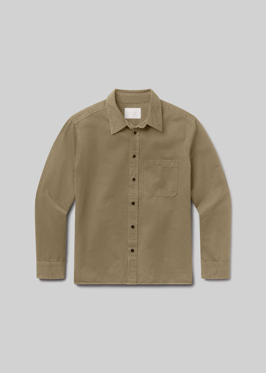 A long-sleeve button-up shirt in a warm khaki or tan color, featuring a classic collar, a single chest pocket, and dark buttons, displayed against a grey background.