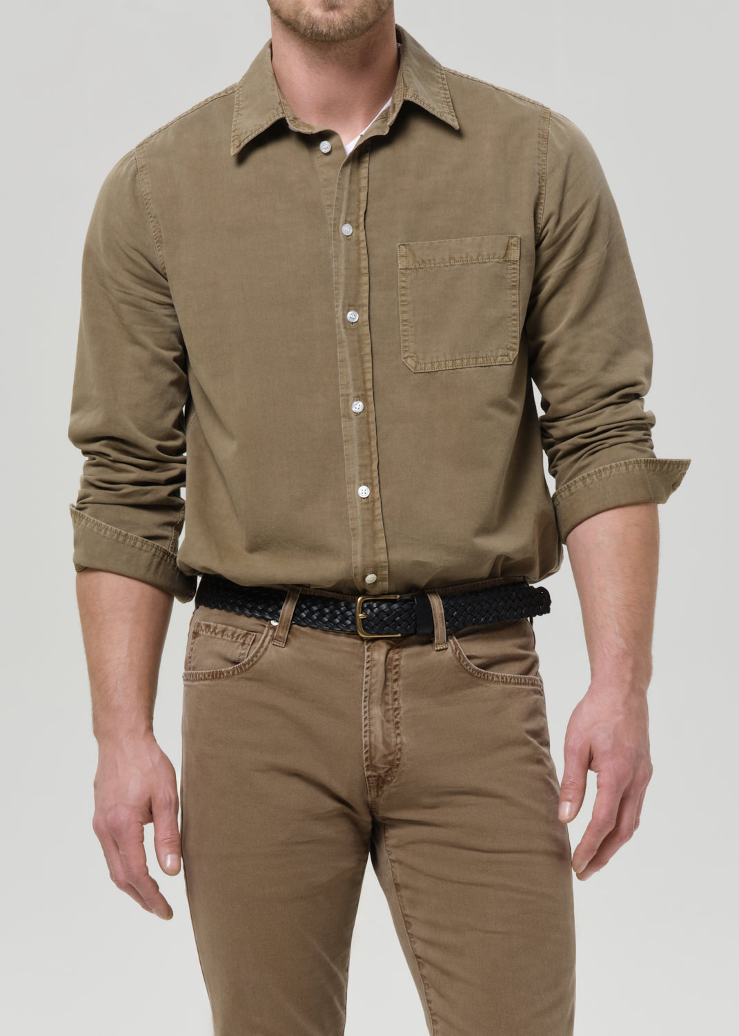 Man wearing a brown shirt and pants on a grey background