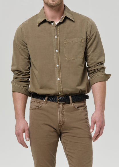 Man wearing a brown shirt and pants on a grey background