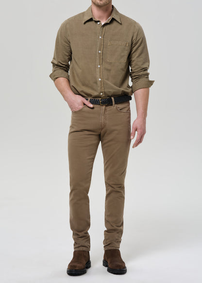 Man wearing a brown shirt and pants with a belt on a grey background