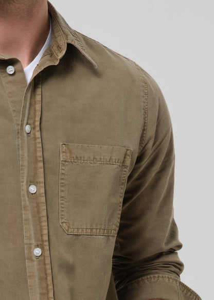 Close-up of a brown button-up shirt with a pocket on a grey background