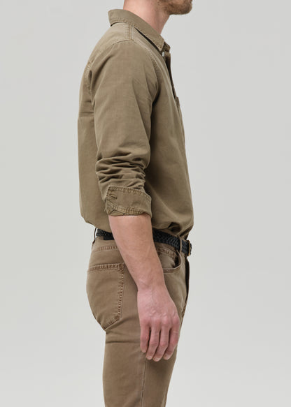 Man wearing a brown shirt and pants on a grey background