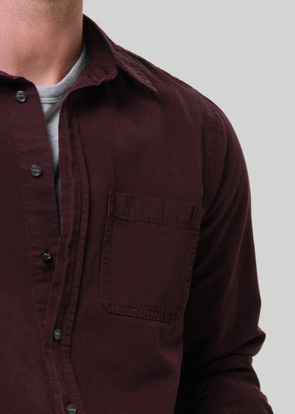 Close-up of a maroon button-up shirt on a grey background
