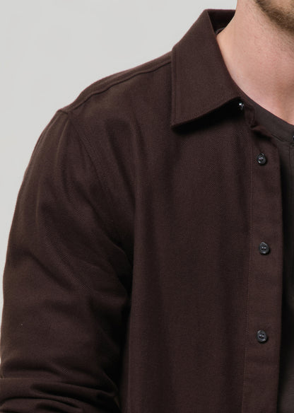 Close-up of a brown button-up shirt on a grey background