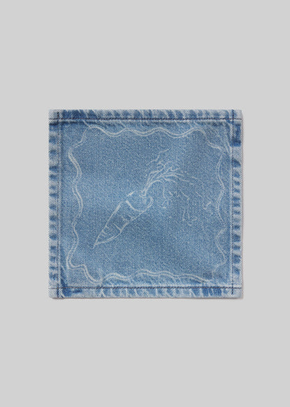 Denim cocktail napkin with carrot embroidered design on a light gray background