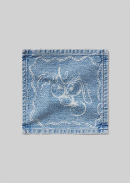 Denim cocktail napkin with tomatoes embroidered design on a light gray background