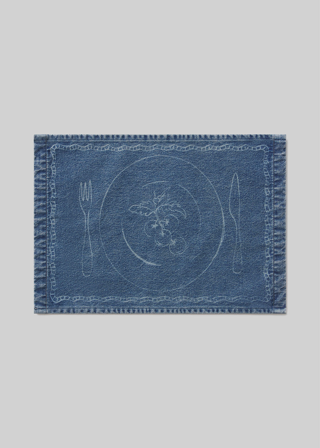 Blue denim placemat with cutlery and tomato design on a light gray background