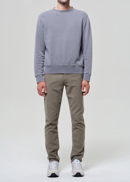 Person wearing a gray sweatshirt and beige pants on a white background
