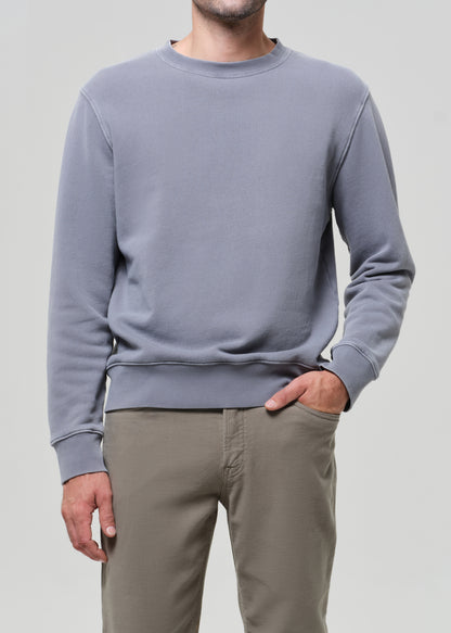 Person wearing a gray sweatshirt and beige pants on a plain background