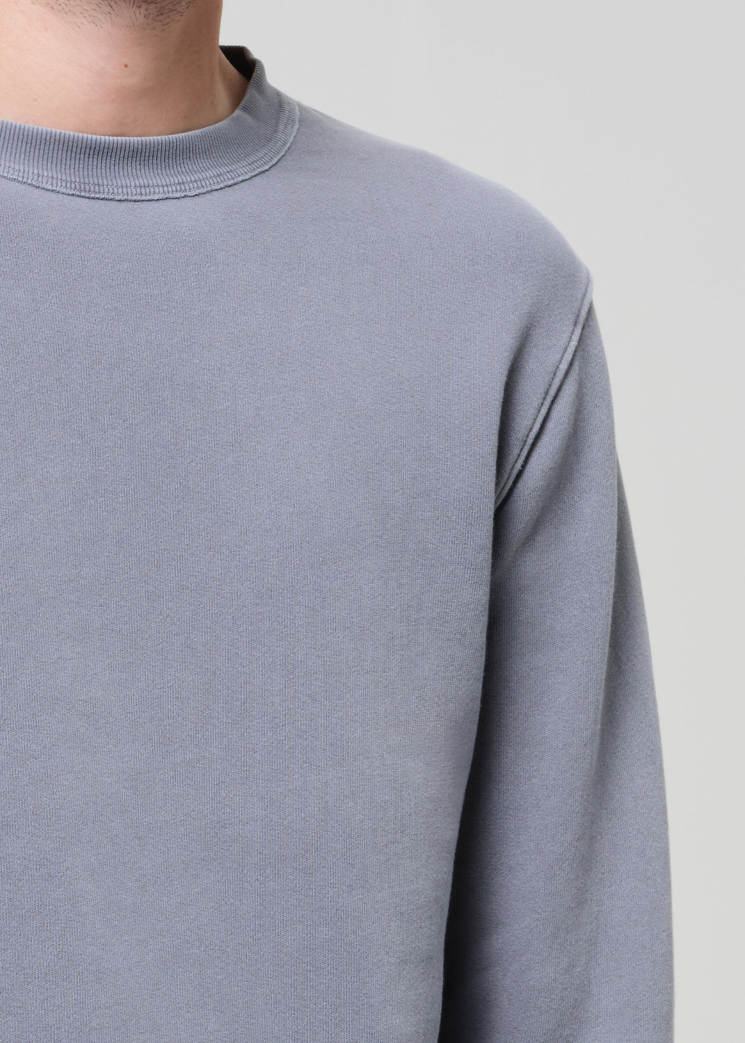Gray sweatshirt worn by a person on a light gray background