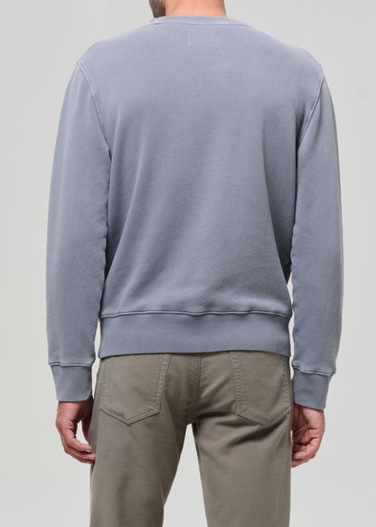 Person wearing a light gray sweatshirt and beige pants on a plain background