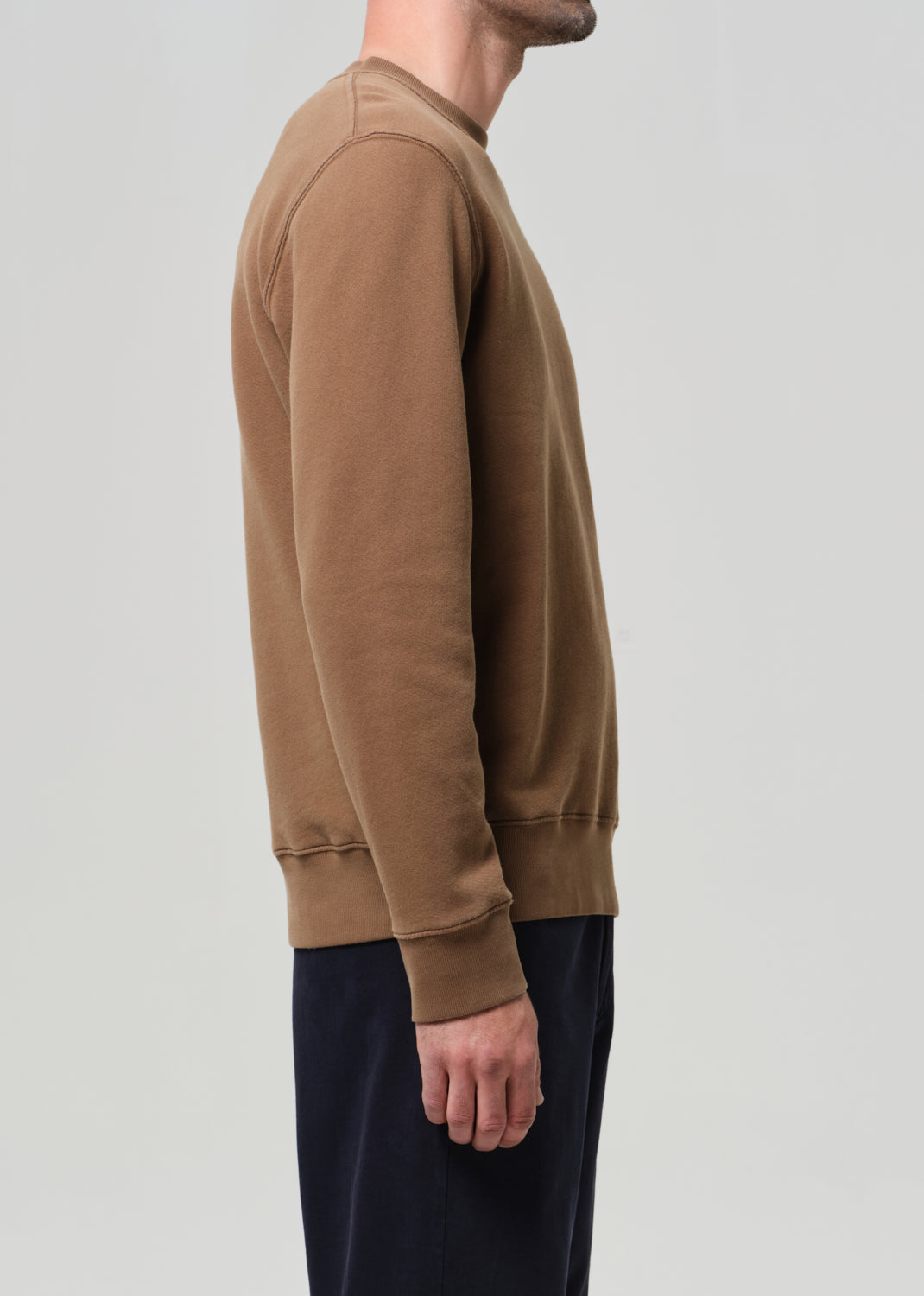Person wearing a brown sweatshirt on a plain background