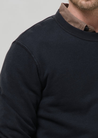 Close-up of a black crewneck sweatshirt on a grey background.