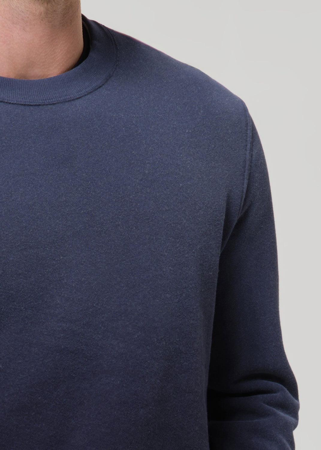 Navy blue sweater worn by a person on a grey background