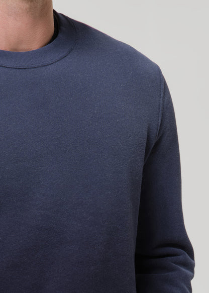Navy blue sweater worn by a person on a grey background