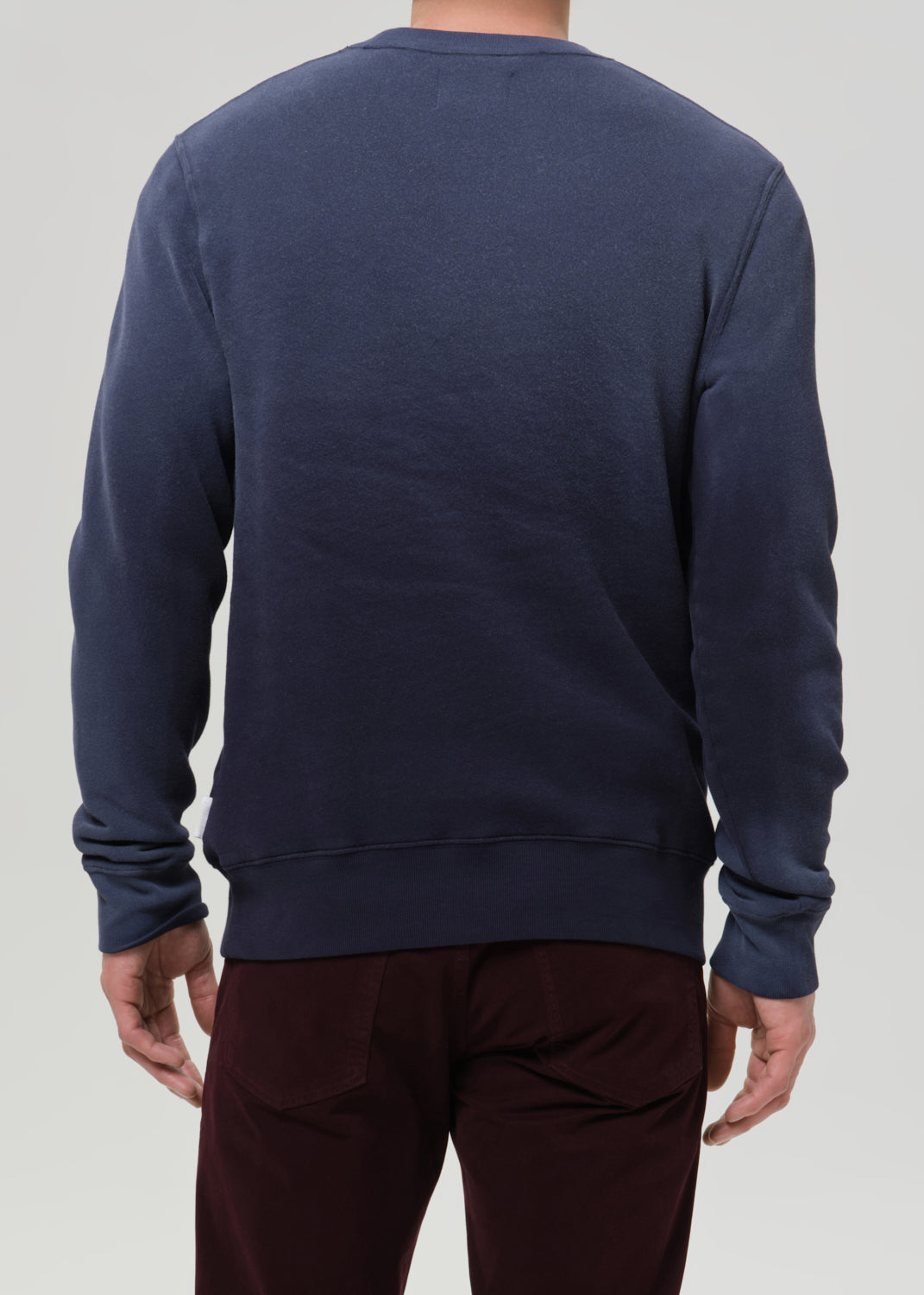 Person wearing a navy blue sweatshirt on a grey background