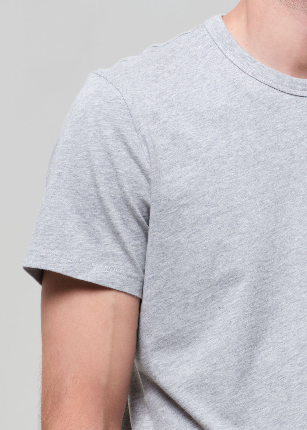 Gray t-shirt worn by a person on a plain background
