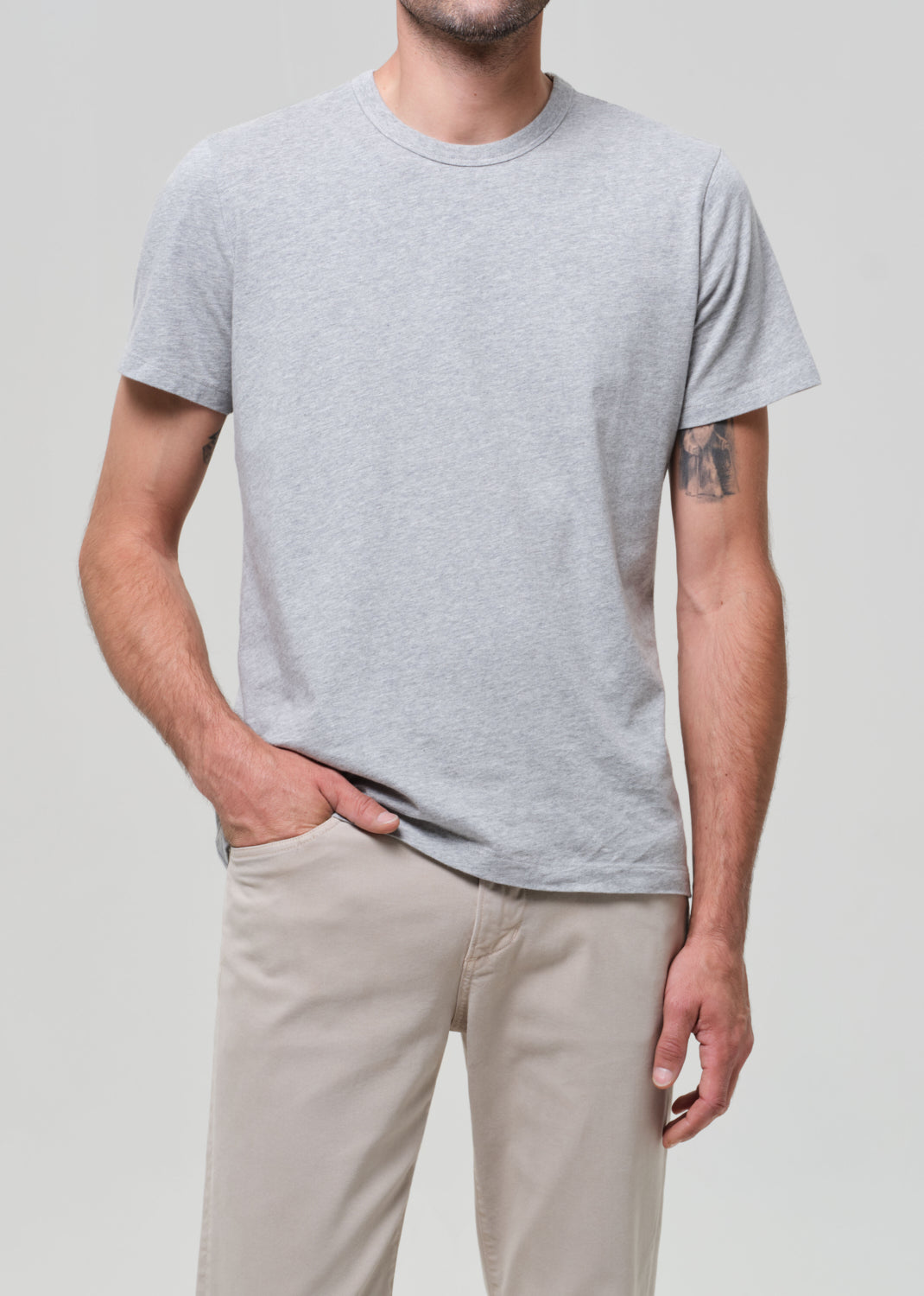 Person wearing a gray t-shirt and beige pants on a plain background