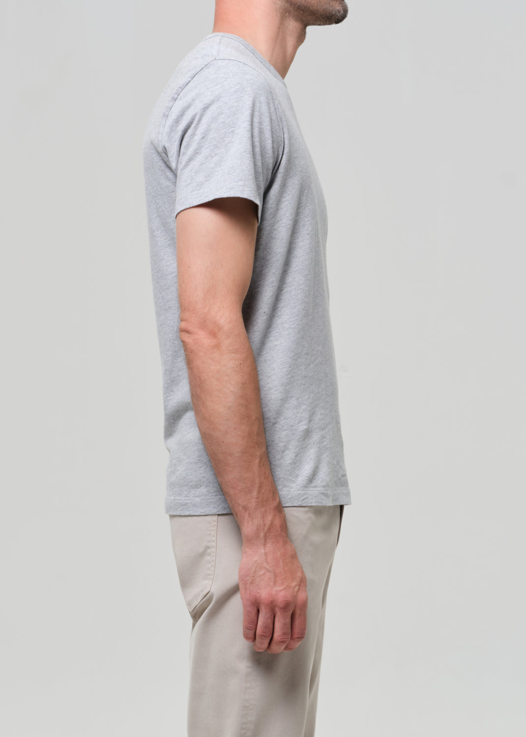 Person wearing a gray t-shirt and beige pants on a light gray background