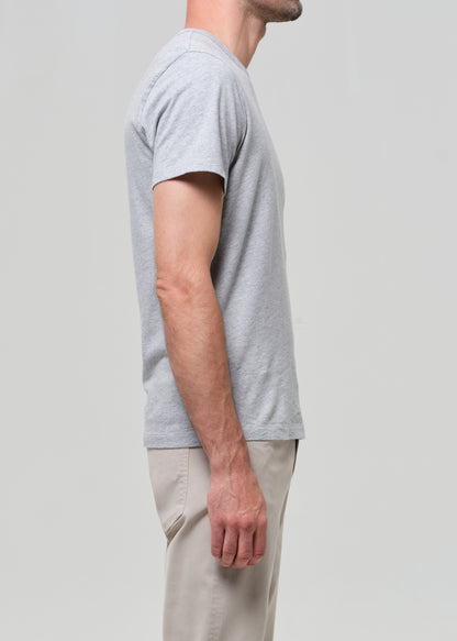 Person wearing a gray t-shirt and beige pants on a light gray background