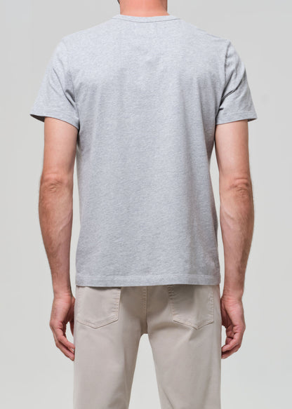 Person wearing a gray t-shirt and beige pants against a plain background