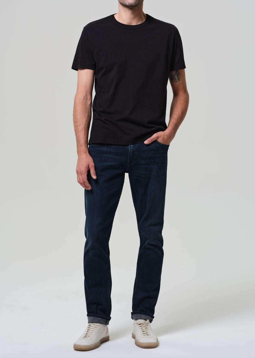 Person wearing a black t-shirt and dark jeans on a white background