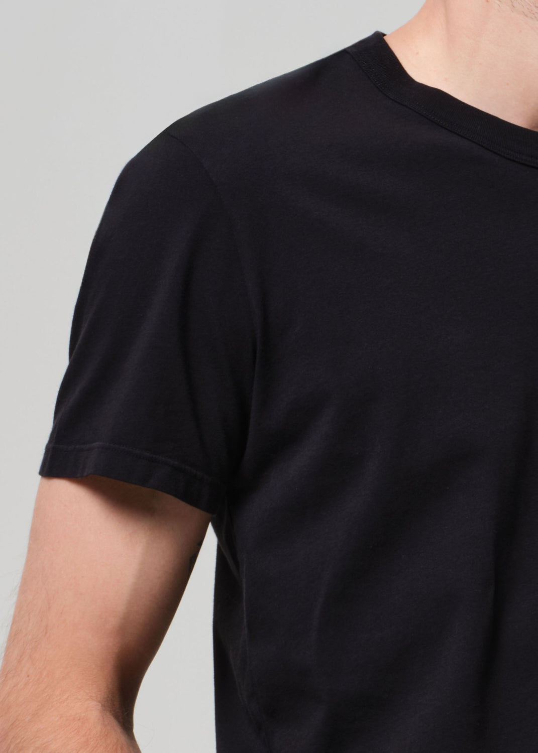 Black t-shirt worn by a person on a plain background