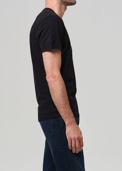 Person wearing a black t-shirt and blue jeans on a light gray background